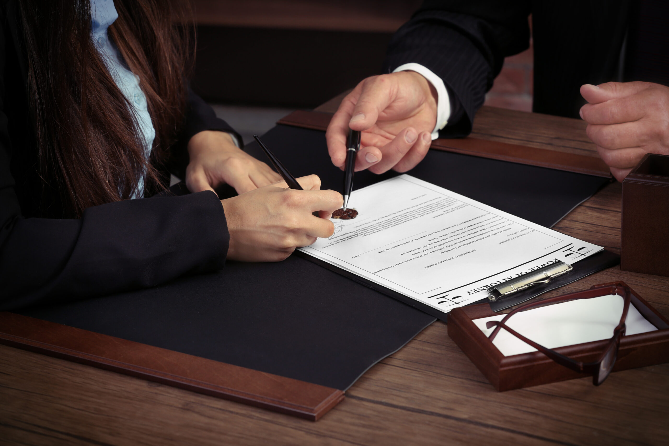 Notary,With,Client,In,Office Two persons' hands showing, holding pens and signing / discussing about a contract